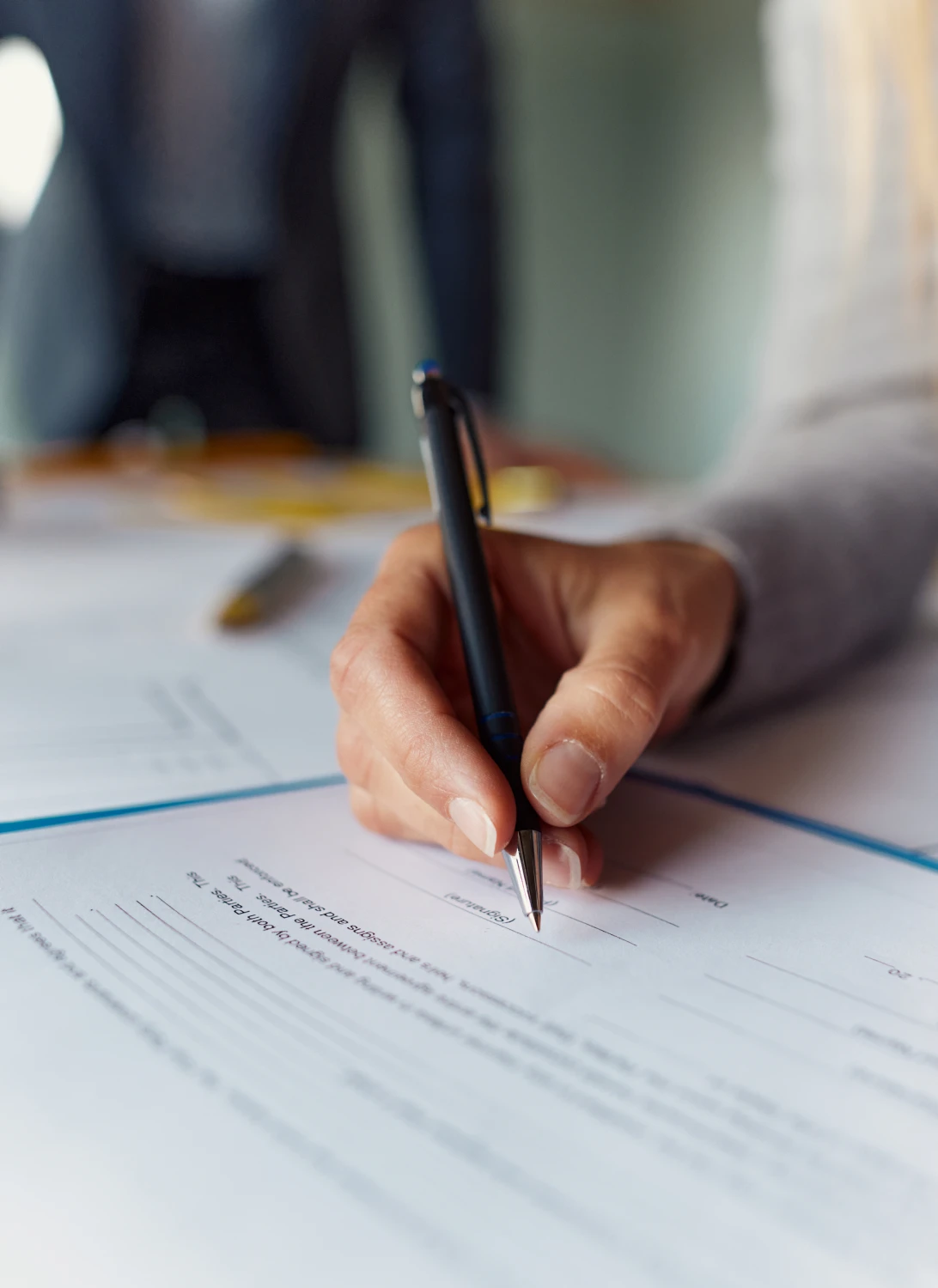 Hand signing a document with a pen